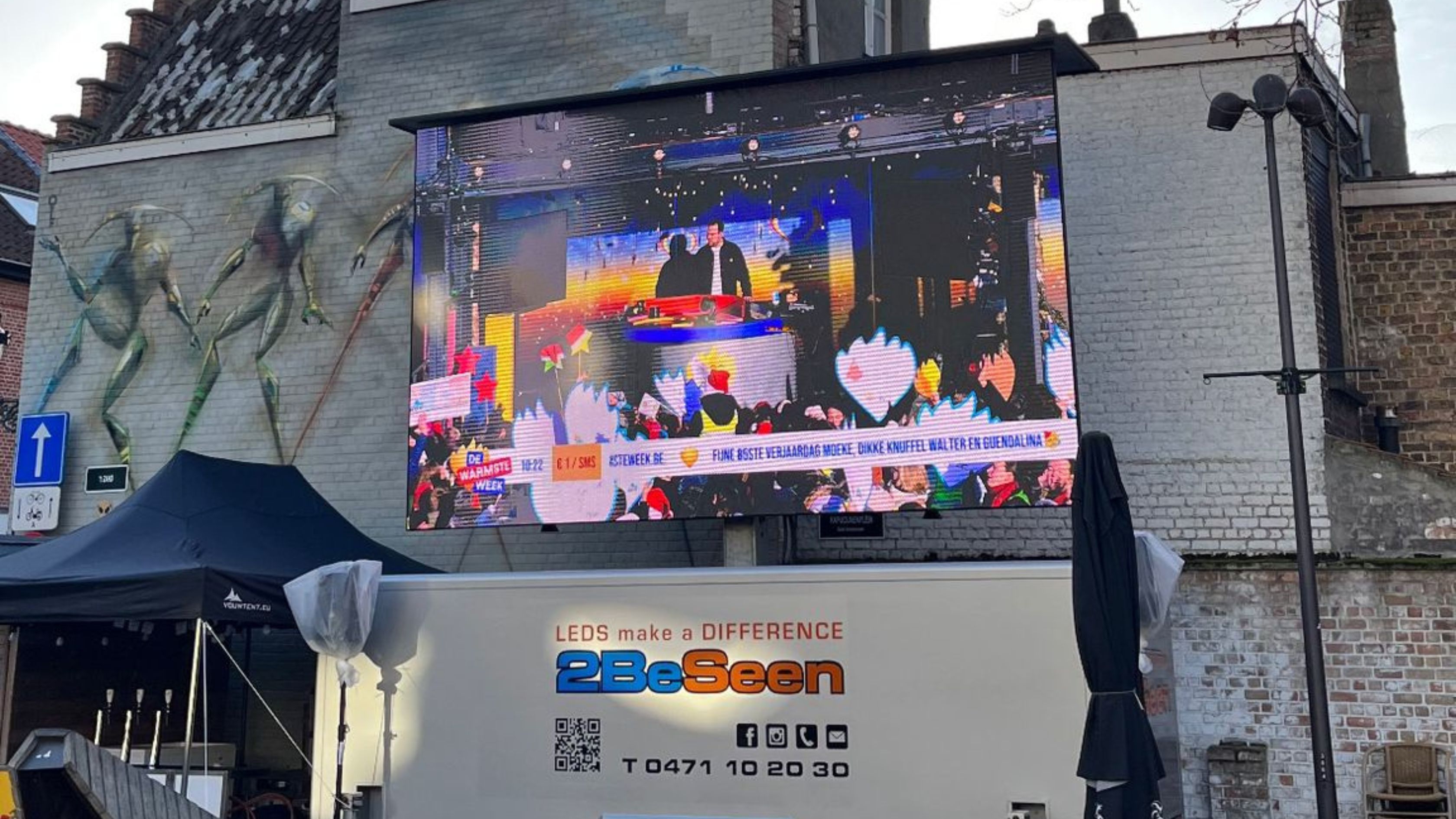 Groot ledscherm met beelden van optredens op De Warmste Week in Brugge