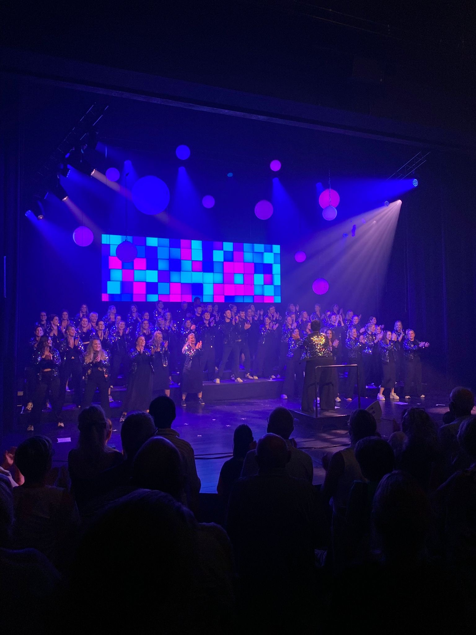 Indoor LED-wall P2.6 van 8 × 2 m achter een popkoor in een theaterzaal